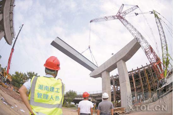 紅易-滬昆跨線(xiàn)橋跨滬昆高速公路主跨架梁施工現(xiàn)場(chǎng)，一節(jié)節(jié)鋼箱梁被吊起安裝。（記者 方陽(yáng) 攝）